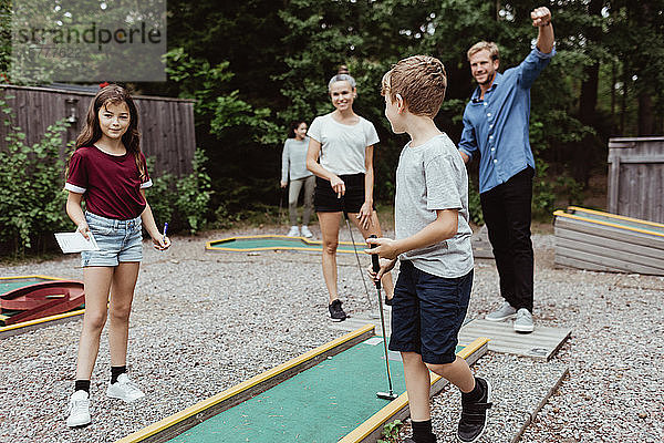 Familie in voller Länge spielt Minigolf im Garten
