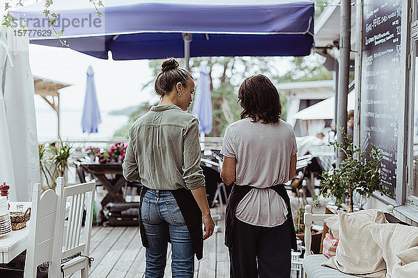 Rückansicht einer Geschäftsfrau mit Mitarbeiterin im Restaurant stehend