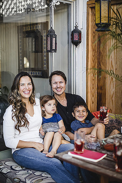 Porträt einer glücklichen Familie  die am Tisch vor einer Glastür sitzt