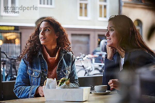 Lesbisches Pärchen  das am Wochenende in der Stadt im Straßencafé sitzt