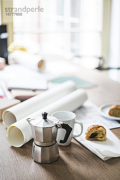 Hochwinkelansicht einer Teekanne mit aufgerollten Dokumenten auf dem Tisch