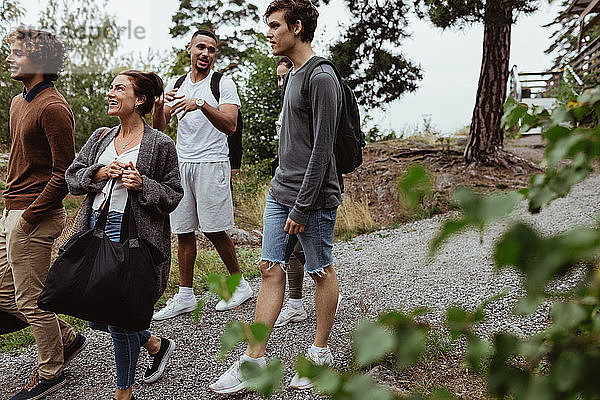 Lächelnde Freunde und Familie im Urlaub auf einem Fußweg zwischen Bäumen