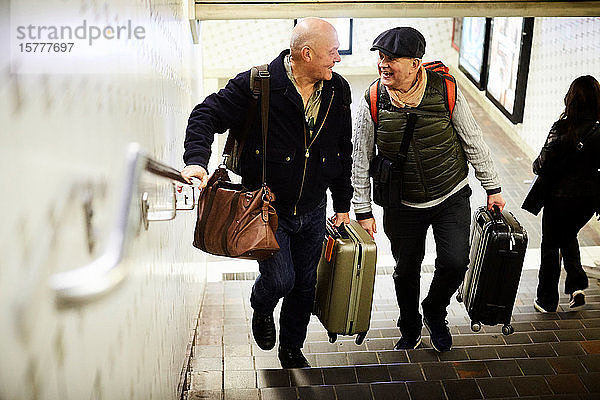 Älteres schwules Ehepaar in voller Länge mit Gepäck auf der Treppe in der U-Bahn