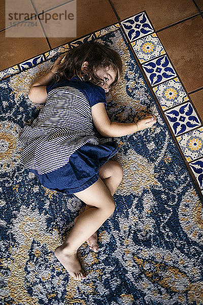 Hochwinkelansicht eines auf dem Teppich liegenden Mädchens