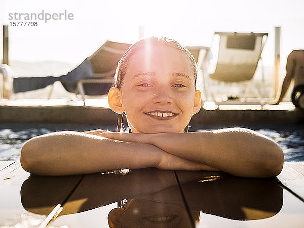 Porträt eines lächelnden Mädchens im Schwimmbad eines Ferienortes gegen den Himmel