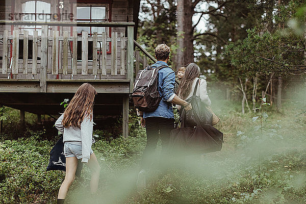 Rückansicht eines Mädchens mit Familie  das auf ein Haus im Wald zugeht