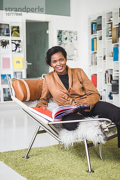Porträt einer selbstbewussten Architektin mit Buch auf einem Sitz im Home-Office