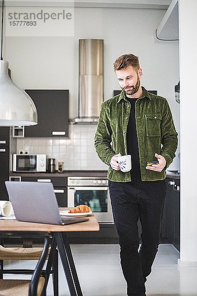 Männlicher Architekt mit Kaffeetasse am heimischen Tisch