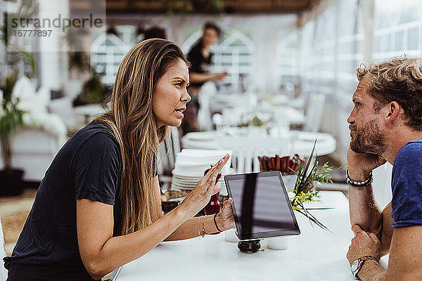 Weibliche Besitzerin nimmt Bestellung von Kunden entgegen  während sie ein digitales Tablet im Restaurant benutzt