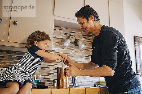 Älterer Vater und Tochter arbeiten in der Küche mit einer Kaffeemaschine mit französischer Presse