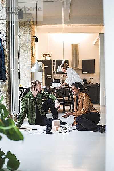 Glückliche Architekten diskutieren  während eine Unternehmerin zu Hause im Hintergrund arbeitet