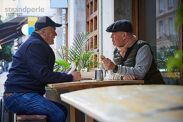 Homosexuelles Paar isst Essen  während es in einem Straßencafé in der Stadt sitzt