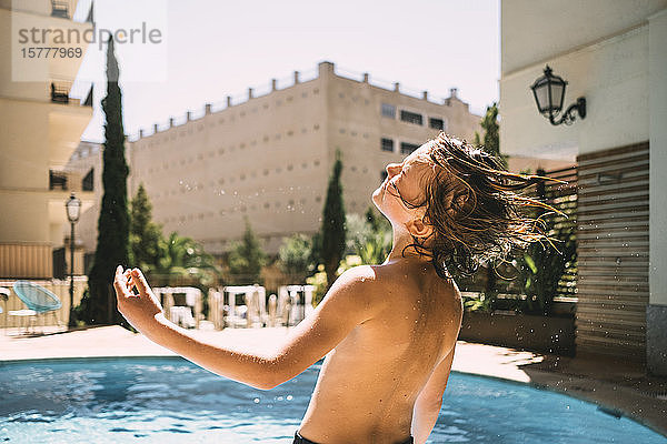 Rückansicht eines hemdlosen Jungen  der sich am Resort-Schwimmbad gegen den Himmel erfreut