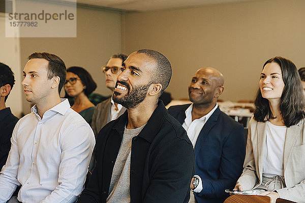 Lächelnde Unternehmer und Unternehmerinnen sitzen im Büroseminar