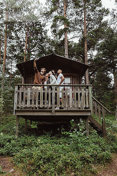 Freunde  die sich mit dem Handy auf der Veranda gegen das Haus stellen