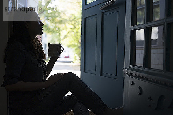 Silhouette einer Frau mit Tasse in der Tür