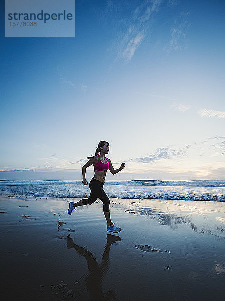 Frau in Sportkleidung läuft am Strand