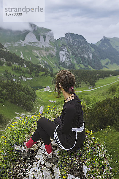 Frau sitzt auf einem Felsen in den Bergen in Appenzell  Schweiz