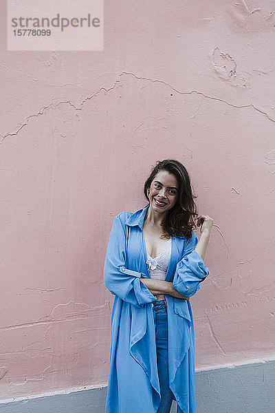 Lächelnde Frau in Blau vor rosa Wand