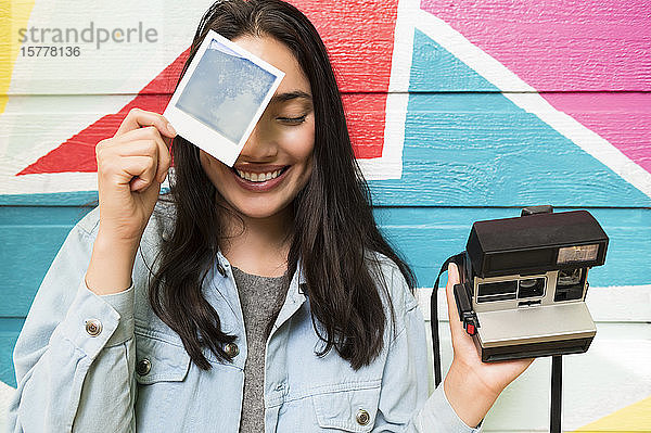 Lächelnde Frau mit Foto und Polaroidkamera