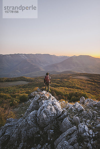 Mann auf einem Felsen in den Bergen bei Sonnenuntergang