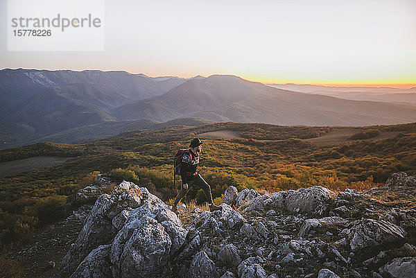 Mann auf einem Felsen in den Bergen bei Sonnenuntergang