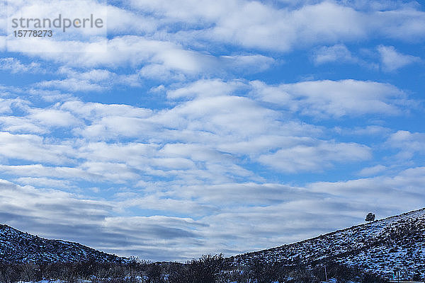 Verschneite Hügel unter Wolken