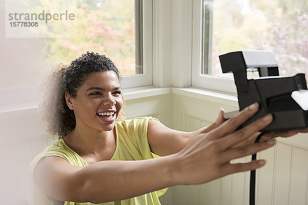 Lächelnde Frau  die ein Selfie mit einer Polaroidkamera macht