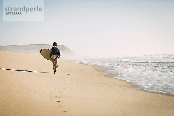 Frau hält Surfbrett am Strand