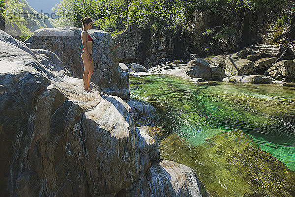 Frau im Bikini auf einem Felsen am Fluss