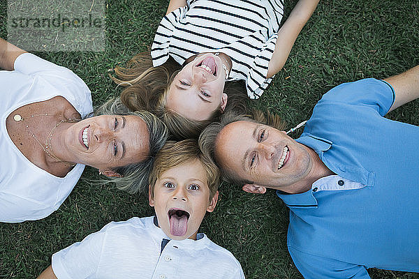 Familie lächelnd im Gras liegend
