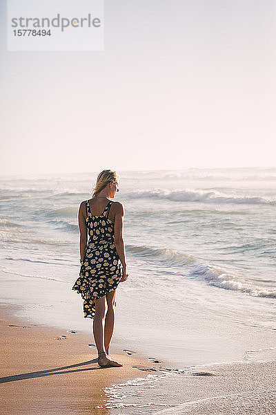 Frau in schwarzem Kleid am Strand