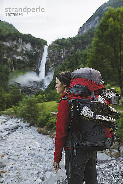 Frau mit Rucksack und Wasserfall in der Ferne