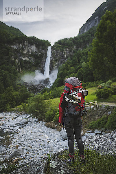 Frau mit Rucksack und Wasserfall in der Ferne