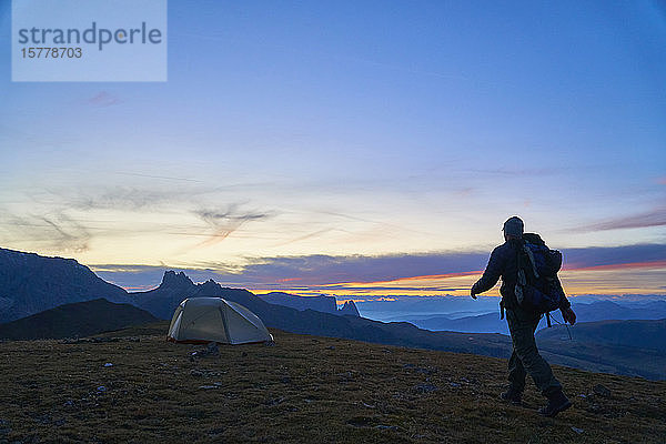 Wanderer auf dem Weg zu seinem Zelt bei Sonnenuntergang  Canazei  Trentino-Südtirol  Italien