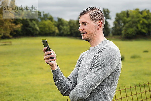 Mann neben dem Feld beim Betrachten eines Smartphones  Francenigo  Venetien  Italien