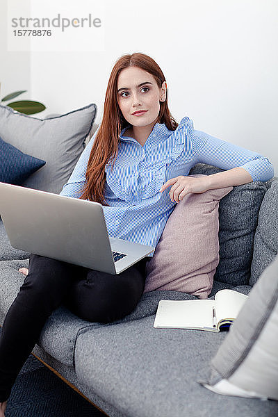 Frau benutzt Laptop auf dem Sofa