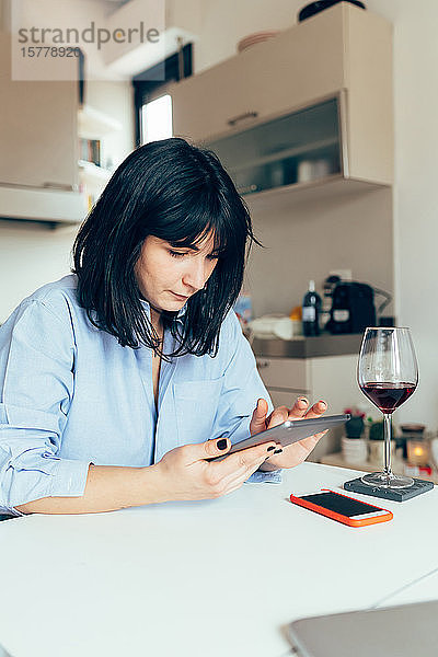 Frau sitzt am Tisch mit digitalem Tablett