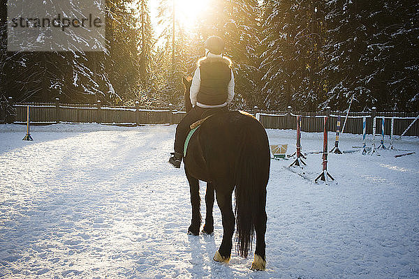 Mädchen reitet Pferd bei Sonnenuntergang