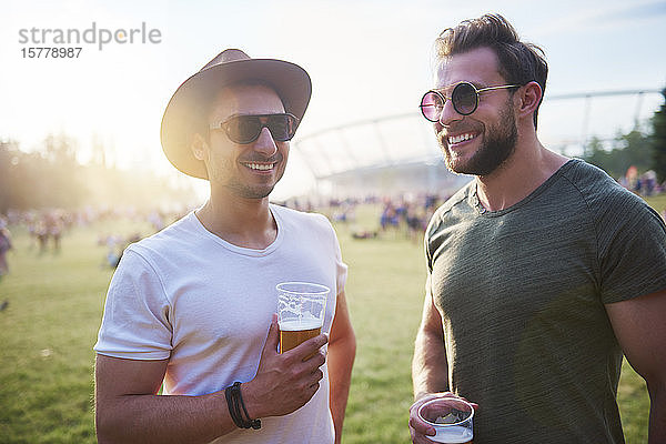Zwei junge männliche Freunde mit Biergläsern beim Holi-Fest