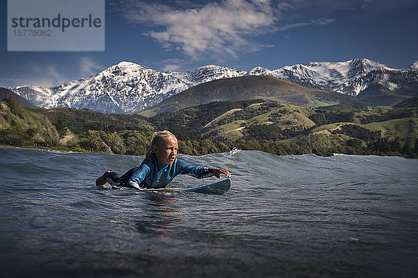 Junge paddelt auf einem Surfbrett im Meer  Kaikoura  Gisborne  Neuseeland