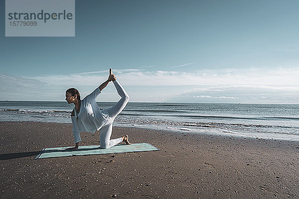 Frau praktiziert Yoga am Strand