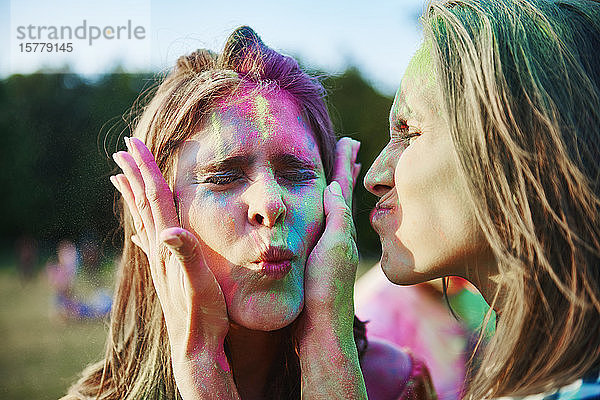 Zwei junge Frauen mit mit farbigem Kreidepulver bedeckten Gesichtern beim Holi-Fest