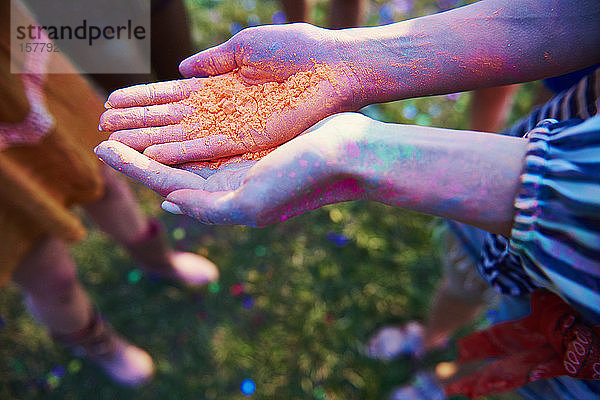 Junge Frau mit Schalenhänden hält farbiges Kreidepulver beim Holi-Fest  Nahaufnahme der Hände