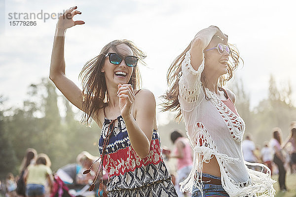 Freunde tanzen mit erhobenen Armen beim Musikfestival