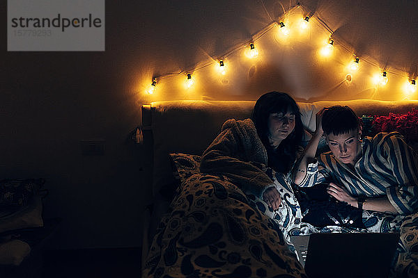 Frauen im Bett im Dunkeln mit Laptop