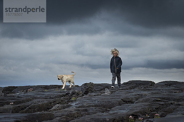 Junge auf Felsen mit Haustier Labradorhund  Doolin  Clare  Irland