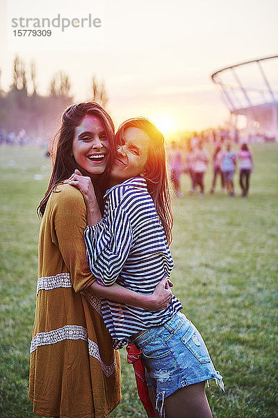 Zwei mit farbigem Kreidepulver bedeckte junge Frauen umarmen sich beim Holi-Fest  Porträt