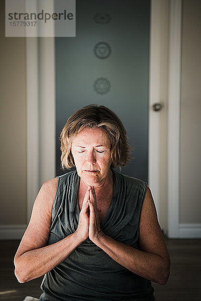 Frau mit geschlossenen Handflächen in Meditationshaltung