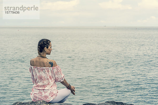 Frau meditiert auf dem Meer